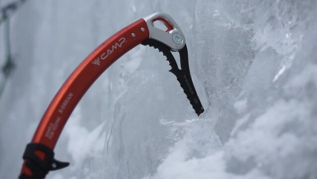 An Ice Climber hammers his Ice Axes into a frozen waterfall.