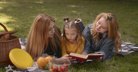 Lgbtq couple with daughter reading a book on picnic