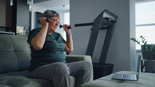 Active Elderly Woman Watching Online Sport Workout At Laptop And Training Alone At Home