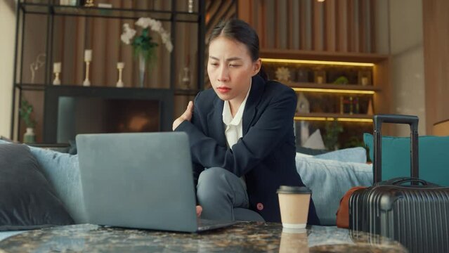 Youth Asia lady passenger formal suit sit on couch eyes focus on computer laptop online work in airline lounge with tea cup wait for transit international airport. Hotel Travel business trip concept.