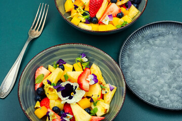 Bright fruit salad with edible flowers.