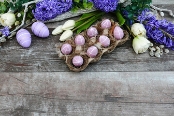  Ostereier mit weißen Tulpen und Hyazinthen auf einem Holzhintergrund mit Platz für Text.