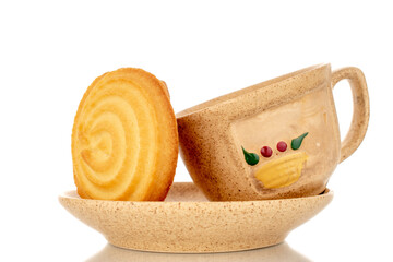 One sweet cookie on a ceramic saucer with a cup, macro, isolated on white background.