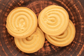 Four sweet cookies on a clay saucer, macro, top view.