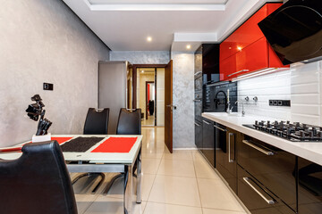 Modern kitchen interior with red and black cabinets and white ceramic floor