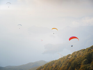 Paragliding in sky. Paraglider tandem flying over sea and mountains in cloudy day. view of paraglider and Blue Lagoon in Oludeniz, Turkey. Extreme sport. Landscape