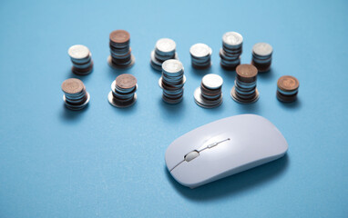 Computer mouse and coins on the blue background.