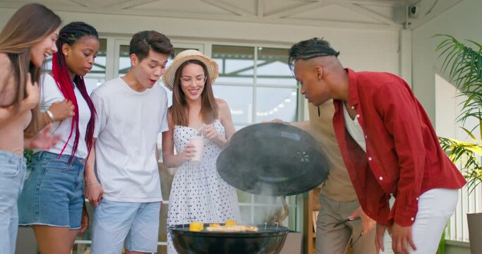 multi ethnic people Enjoying Outdoor BBQ. Happy people having barbecue in garden, men women smell meet sausages corns, enjoyment, people get pleasure from BBQ Party slow motion.mouth's watering dish