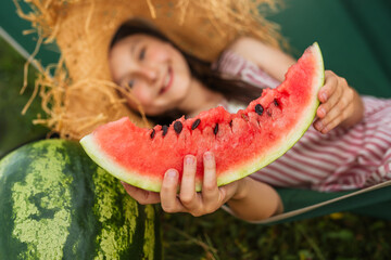Little happy kid eating watermelon. Child is resting in hammock in nature. Top view. Close up.