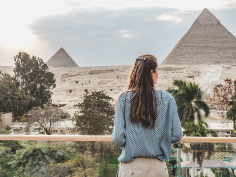 Stylish woman against the background of the Giza pyramid complex. Clear, sunny day, blue sky. Vacation and travel concept