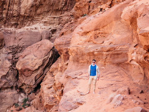 Stylish man and the sights of the Wadi Rum desert in Jordan. Clear, sunny day. Vacation and travel concept