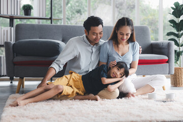 Asian kid cute girl lying on mom and dad happy living relaxing with young mom and dad at home, Happy young family living concept