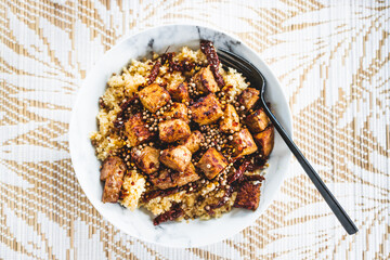 plant-based couscous with grilled tempeh cubes topped with chilli flkes and coiander seeds