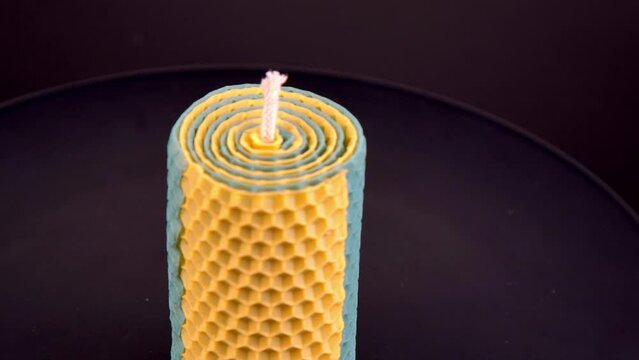 Yellow and blue beeswax candle. A product of beekeeping. Wax candle DIY. Bee honeycomb handmade craft. Top view. Aroma therapy. Romance decor. Black table background