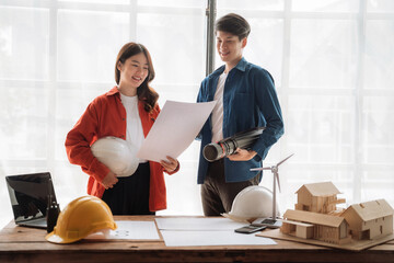 Young couple asian using laptop and looking into the blueprints of their new home.