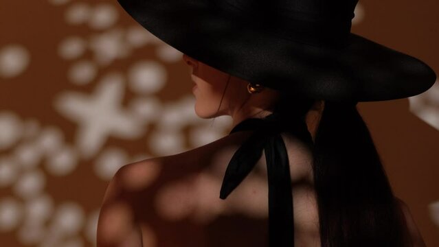 Fashion portrait of a girl in the studio with a black hat with golden decorations. Jewelry