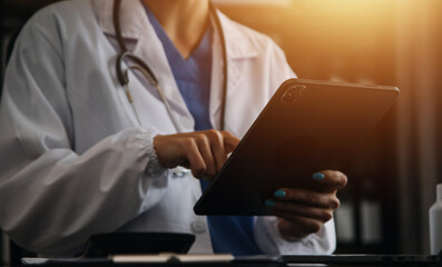 Doctor working with laptop computer and writing on paperwork. Hospital background.