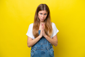 Young caucasian woman isolated on yellow background keeps palm together. Person asks for something