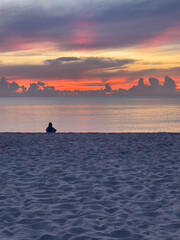 man sitting alone on beach at sunrise