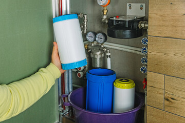 Replacing the filter element in the home water purification system close-up. View through the open hatch in the bathroom
