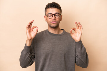 Fototapeta premium Young Brazilian man isolated on beige background in zen pose