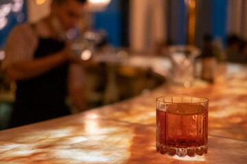 A glass of cocktail on illuminated counter bar