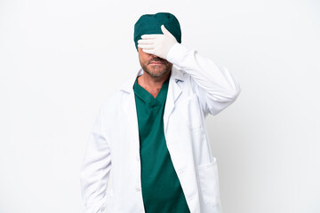 Naklejka na ściany i meble Middle age surgeon in green uniform isolated on white background covering eyes by hands. Do not want to see something