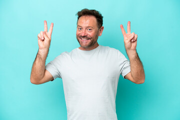 Middle age caucasian man isolated on blue background showing victory sign with both hands