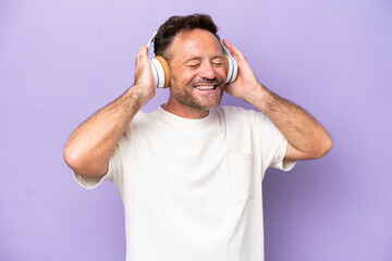 Middle age caucasian man isolated on purple background listening music and singing