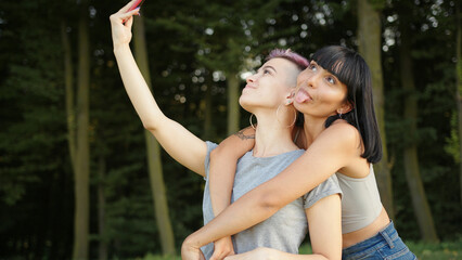 Happy loving homosexual lesbian LGBT couple taking a selfie on the smartphone and kissing