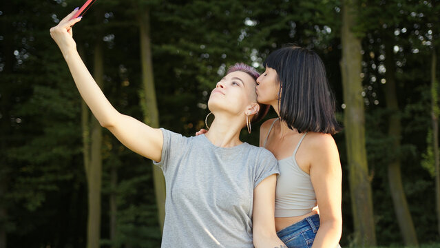 Happy loving homosexual lesbian LGBT couple taking a selfie on the smartphone and kissing