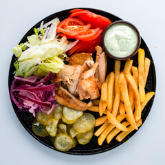 Fresh french fries with chicken, tomatoes, lettuce, pickled cucumbers and sauce.