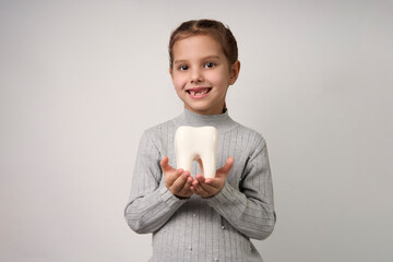 Little girl holding tooth on a white background