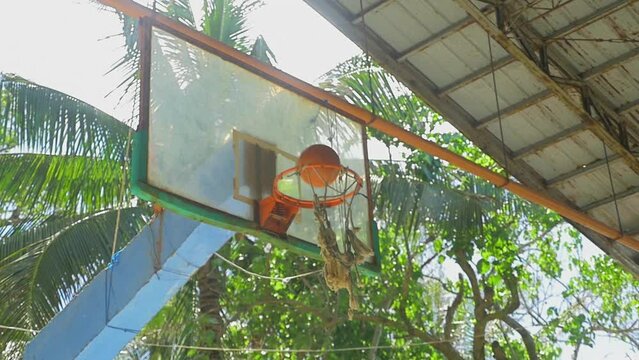 A young man scores in a basketball hoop, in a shed in the middle of nowhere, in the Philippines