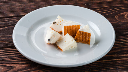 Pieces of smoked cheese in a ceramic plate.