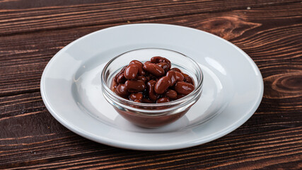 Black olives in a glass bowl on wooden table.