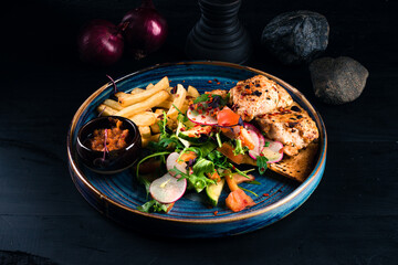 Fried chicken fillet with French fries and fresh vegetable salad.