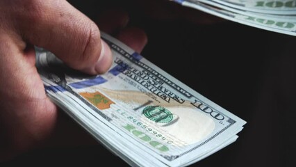 Fingers scroll and shift new 100 dollar bills. Shopping for cash. Payment of expenses. Family budget and savings. Modest income