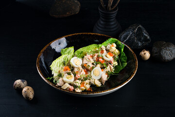 Fresh salad Olivier from boiled vegetables, eggs, sausage, red caviar, greens and mayonnaise.