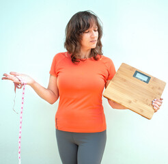 Woman holding measurement tape and  weight scales