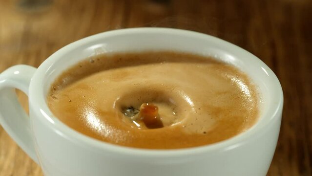 Super Slow Motion Detail Shot of Coffe Drop Falling into Fresh Espresso at 1000 fps. Camera move.