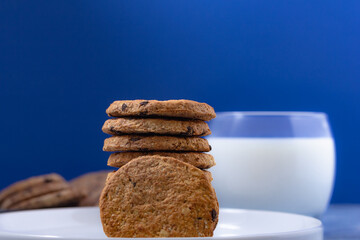 Delicious breakfast of oatmeal cookies with milk on a blue background in a soft morning