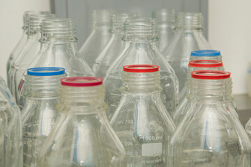 Close-up of a group of glass laboratory bottles without caps on a shelve.