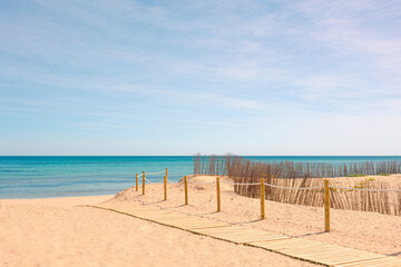 Sunny day on the beach with wooden walkway on the golden sand
