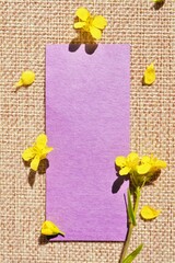 ジュート麻の布を背景に黄色いセイヨウアブラナの花を飾ったオシャレなタイトルスペースのモックアップ、縦 © cattosus