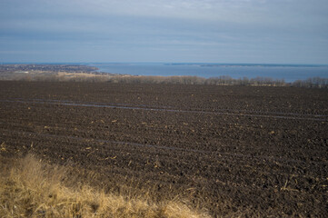 early spring landscape with agricultural field near Dnipro river down to  outskirts of...