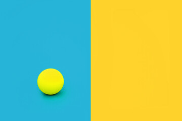 Dare to be different and independent concept with vivid blue and yellow contrast background with ball. Minimal solitary, alone, leadership, stand out in a crowd composition. Flat lay, copy space.