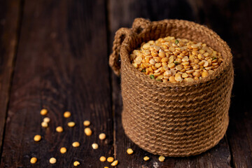 Dry yellow pea grains in a jute bag on a dark wooden table