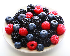 Blackberries, raspberry and blueberrys on white plate.