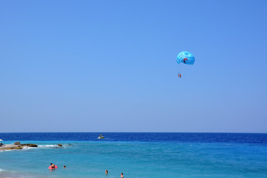 A blue parasail is flying over the ocean isolated with blue sky on background 
